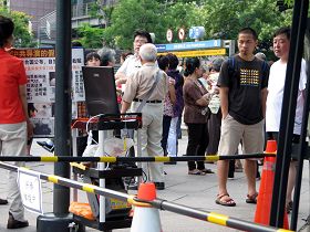 大陆游客正仔细观看法轮功学员播放的真相影片，一旁的郭伯伯（白头发）正与游客劝三退（退出中共党、团、队等组织）