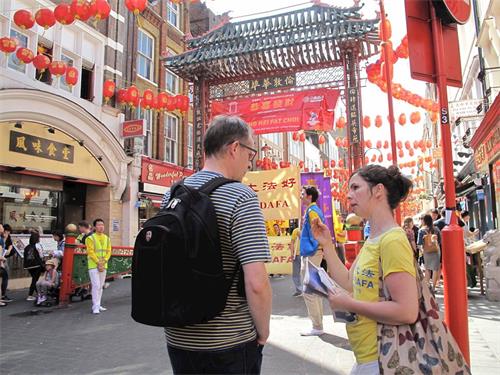 '图14~16:纪念“万名法轮功学员北京和平上访十九周年”伦敦游行过程中,法轮功学员在向路人发传单、讲真相'