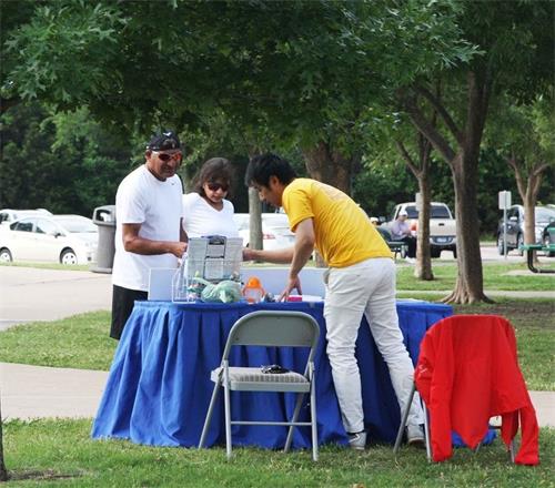 '图4~5:周末来公园散步、健身的人们为法轮功学员集体炼功所吸引,前来了解相关信息。'