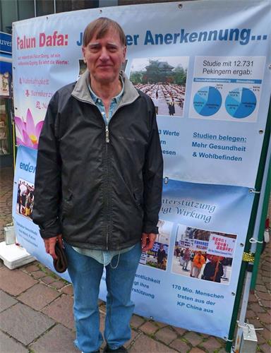 '图6：雷贝格在横幅前，他表示非常认同“真善忍“的理念'