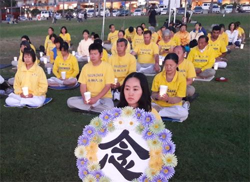 &#039图8～9：夜幕降临之际，法轮功学员们手持烛光排坐在草坪上举行烛光夜悼&#039