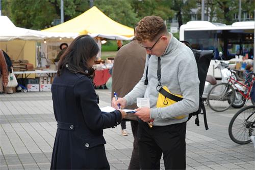 '图11:安诺·迪尔曼为法轮功学员的请愿签字,认为德国政府为制止迫害做的太少'