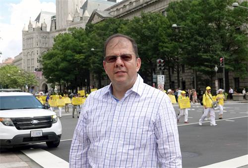 '图18:在一个国际组织工作的艾尔第一次听说法轮功,他说这么多人冒着酷暑走在宪法大道上,一定事关重大。'