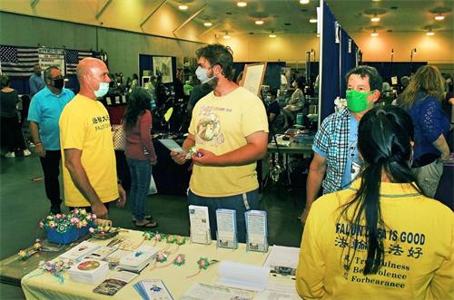 '图1～3：二零二零年十一月二十一日至二十二日，法轮功学员在坦帕市健康博览会设立展位，不少参观者在展位前与学员攀谈，了解真相。'