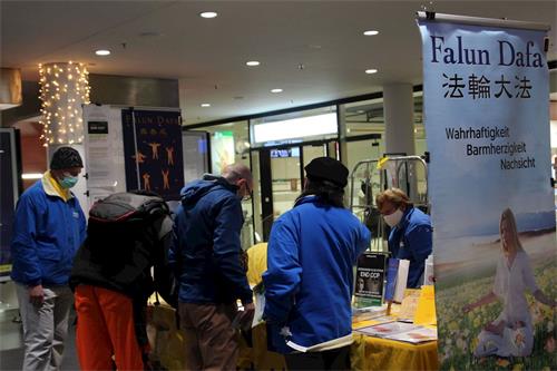 '图15：虽然学员已经在整理摊位，阿劳火车站的路人还是驻足签名表示自己对法轮功的支持'