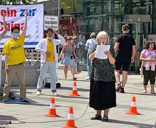 '图1:法轮功学员在演讲,告诉民众中共对法轮功学员的残酷迫害的原因和手段,呼吁人们签署反对中共活摘器官的请愿书。'