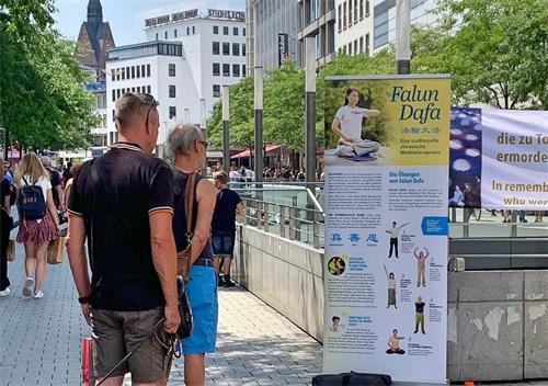 '图2~7:过往的行人在信息台前了解法轮功以及在中国发生的对法轮功学员迫害的信息。'