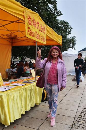 '图24:克里西亚(Krysia)女士路过法轮功展台,表示:我赞颂法轮大法'