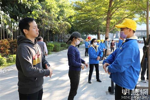 '图13：卢女士（中）正在活动现场旁学炼法轮功。'